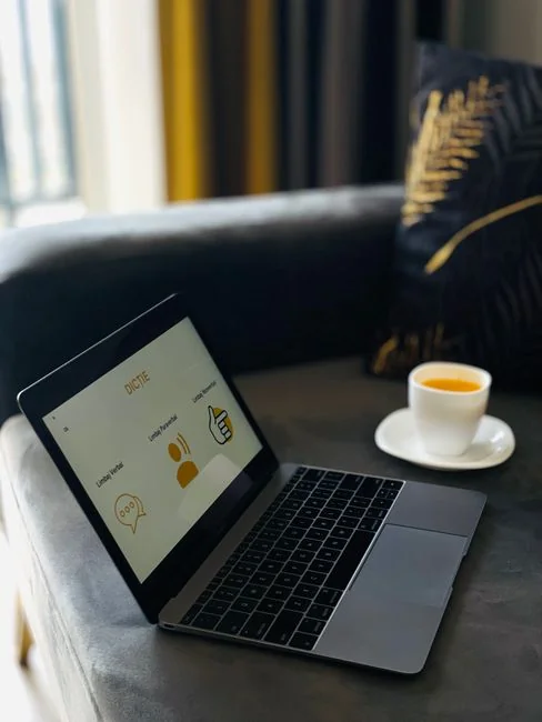 A laptop on a bed showing web design software, creating a cozy workspace.